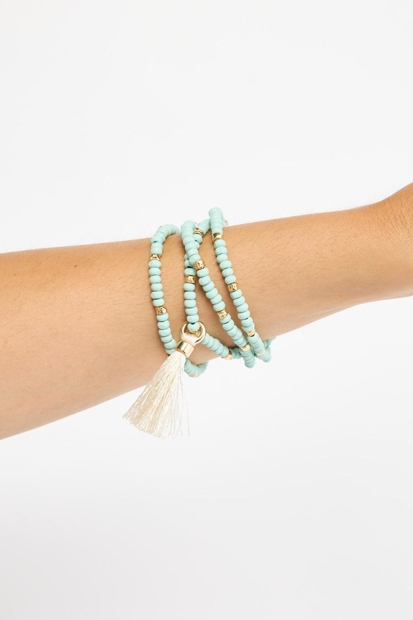 Mckenzie Bracelet worn on the wrist, showing the multi-wrap blue beaded strands and cream tassel charm