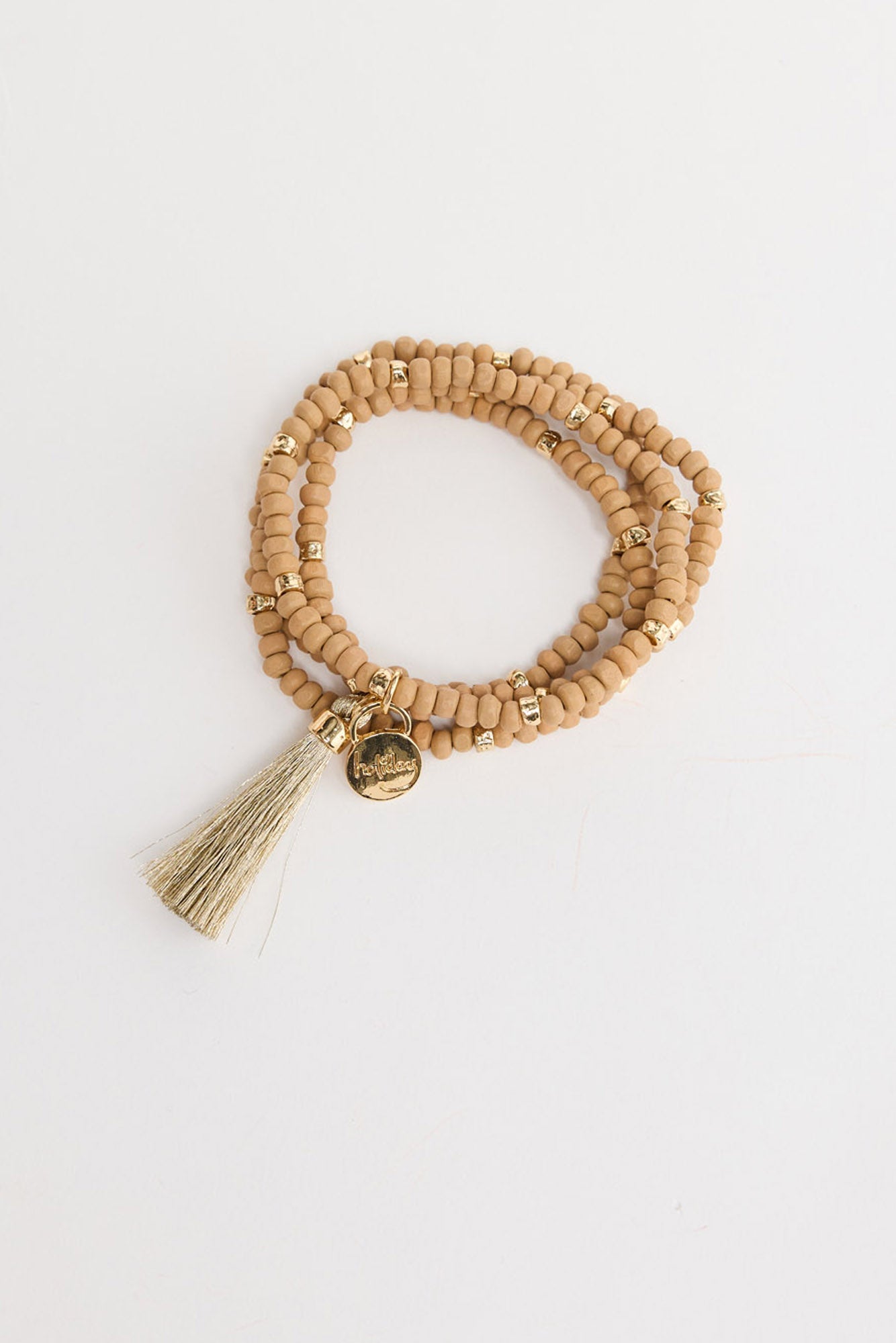 Mckenzie Bracelet in taupe worn on the wrist, showing the multi-wrap beaded strands and gold tassel charm