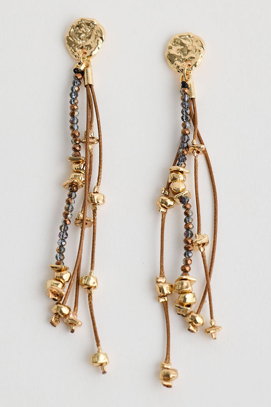 Gold earrings with dangling elements on a light gray background
