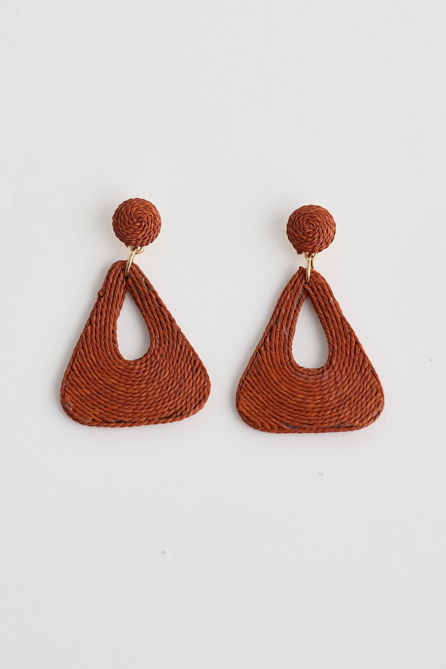 Pair of brown woven earrings on a light gray background