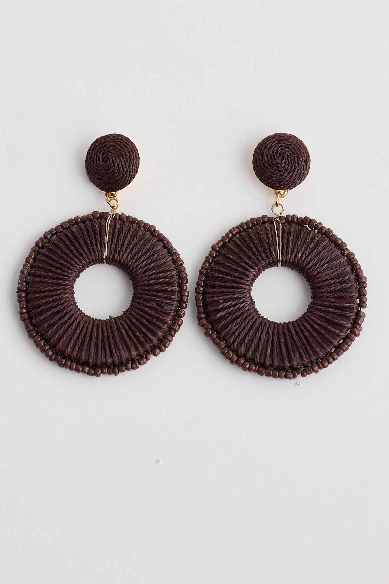 Pair of brown circular earrings on a white background