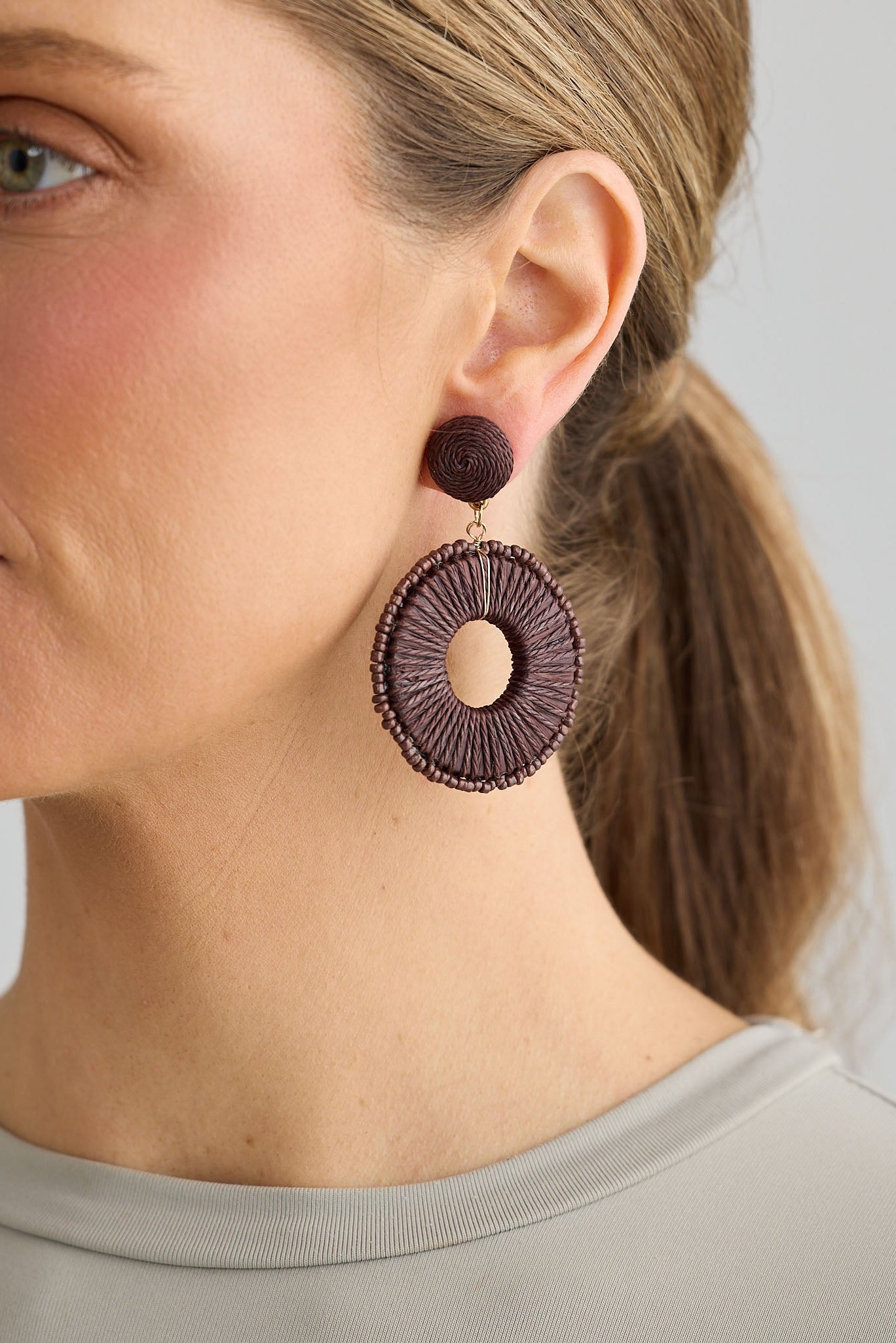 Woman wearing large round earrings on a plain background
