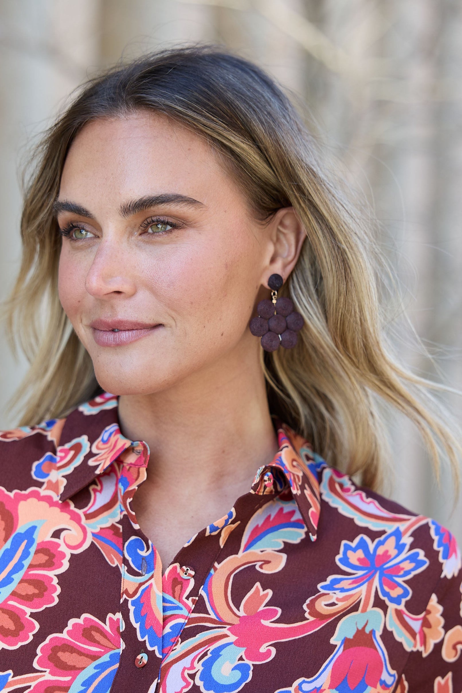 Woman wearing a colorful floral blouse with a blurred natural background