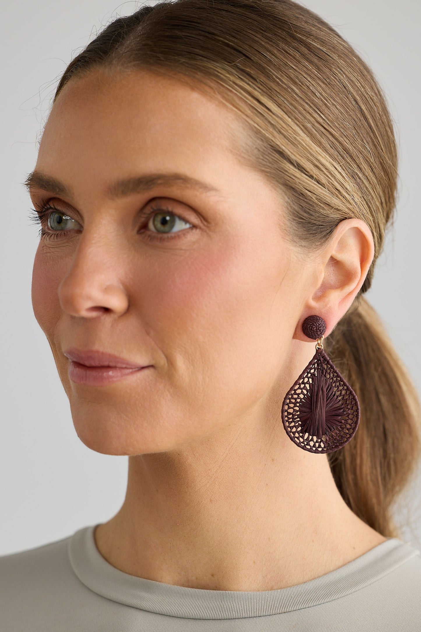 Woman wearing a pair of brown earrings against a neutral background