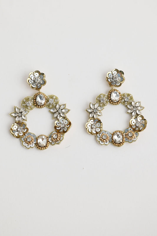 Pair of gold hoop earrings with floral and gemstone details on a light gray background