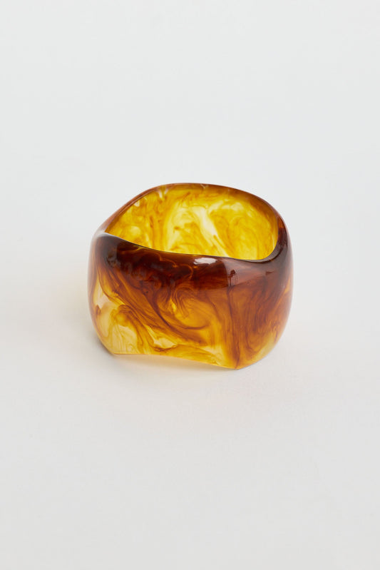 Marbled brown and yellow bangle on a light gray background