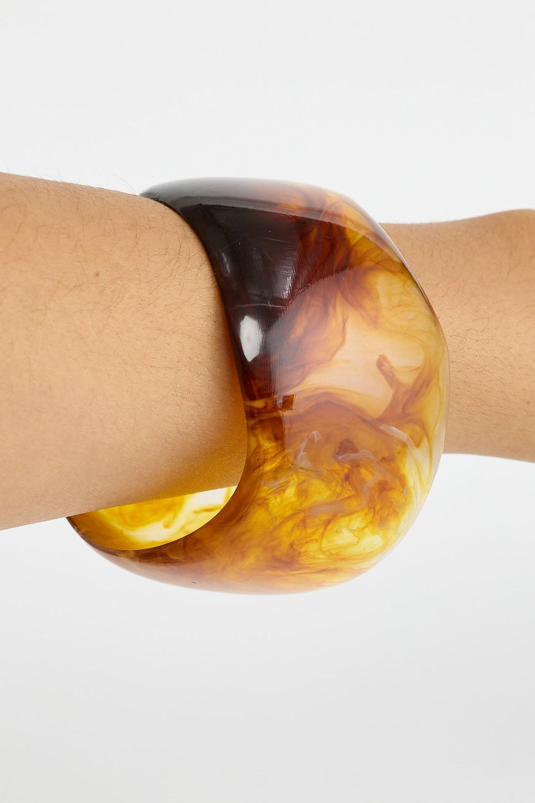 Tortoiseshell bangle on a wrist against a white background