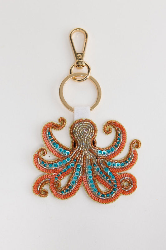 Beaded octopus keyring in coral, turquoise and gold tones with a gold clasp and keyring, laid flat on a white background