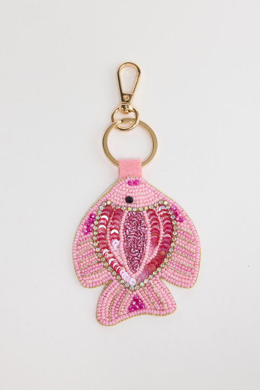 Beaded fish keyring in soft pink seed beads with hot pink and fuchsia sequin scales, crystal border detail and a black bead eye, attached to a gold-tone clasp and split ring via a pink leather tab, shown on a white background