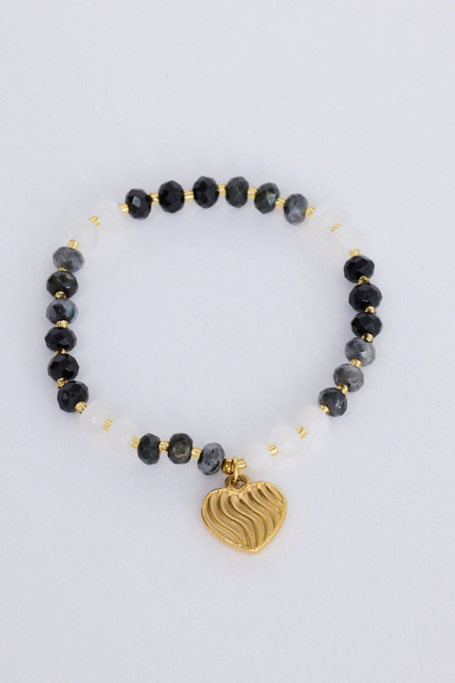Huda Bracelet in black with statement gold charm detail, front view on white background