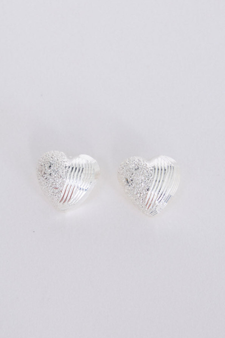 Gabby Earrings in silver with fine textured detailing, angled view on white background