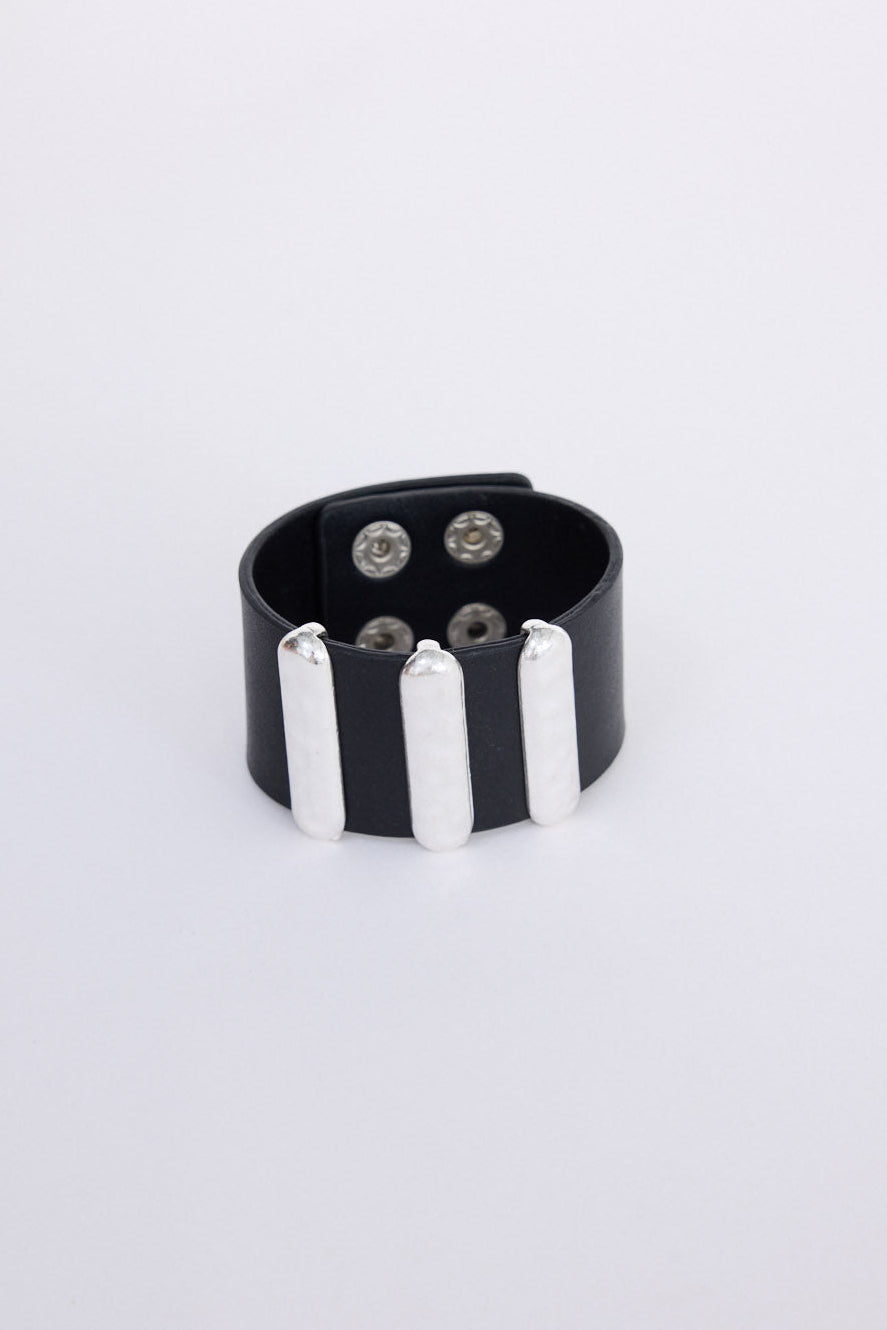Anima Cuff in black with bold metal bar detailing, front view on white background