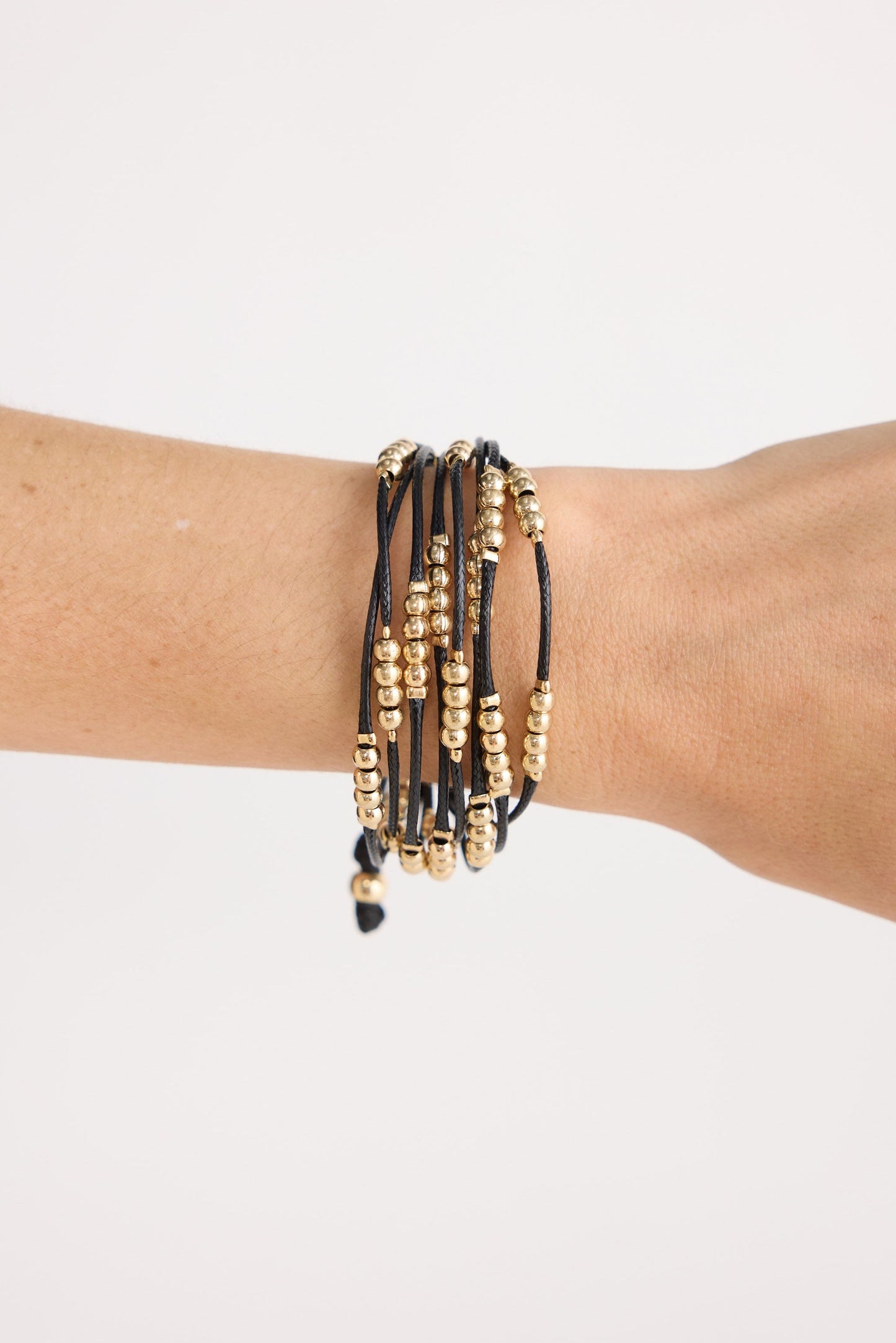 Model wearing Ali Bracelet in black with Gold with mixed bead detailing, angled on-wrist view on neutral background