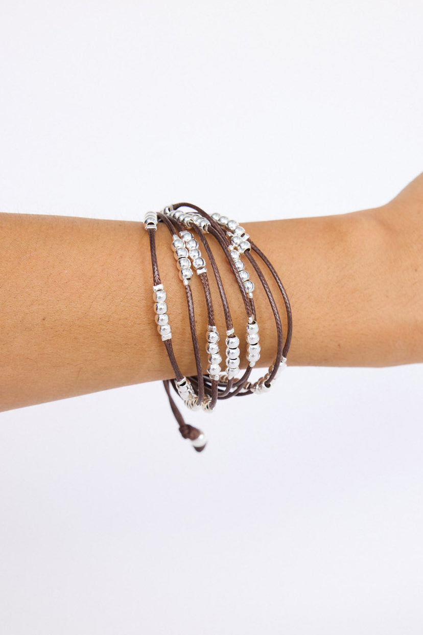 Model wearing Ali Bracelet in brown with Silver with mixed bead detailing, on-wrist view on neutral background