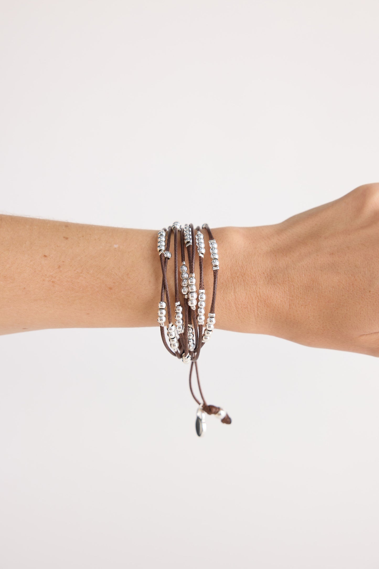 Model wearing Ali Bracelet in brown with Silver with mixed bead detailing, angled on-wrist view on neutral background