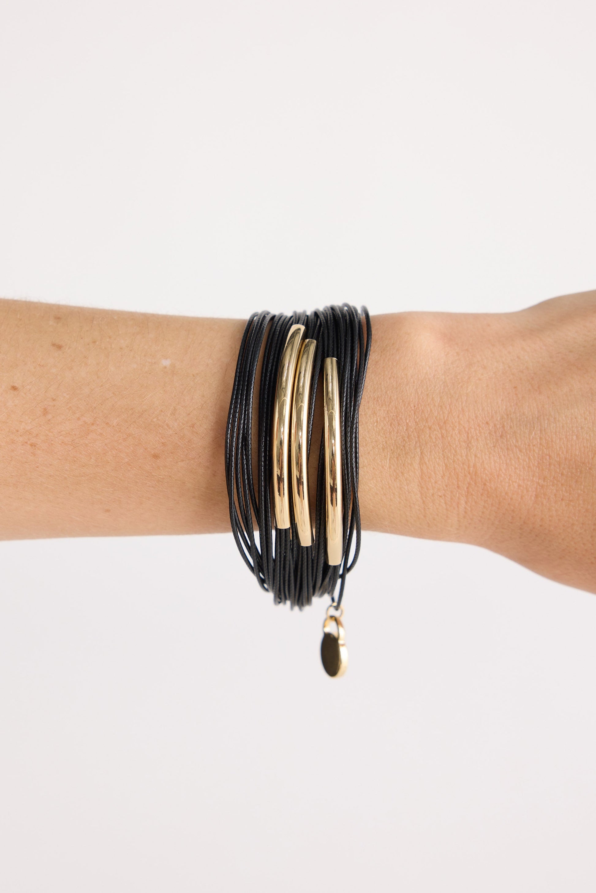 Model wearing Shakira Bracelet in black with metal accent bars, angled on-wrist view on neutral background