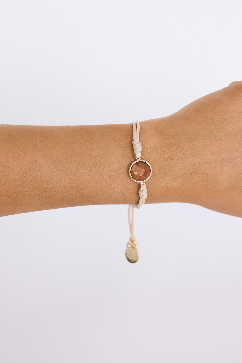 Model wearing Hamilton Bracelet in beige with central stone feature, on-wrist view on neutral background