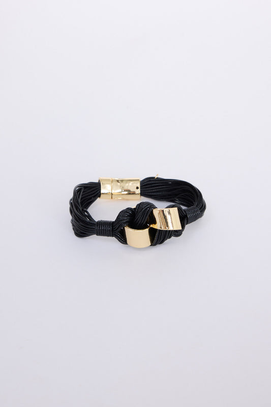 Kazima Bracelet in black with bold knot detailing and metal accents, angled view on white background
