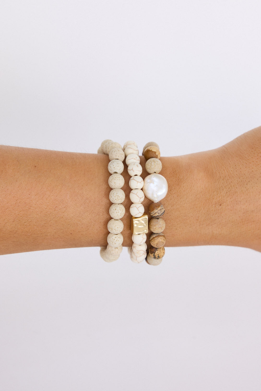Model wearing Solaro Stack Bracelet in natural with natural stones and mother of pearl feature bead, close-up on-wrist view on neutral background
