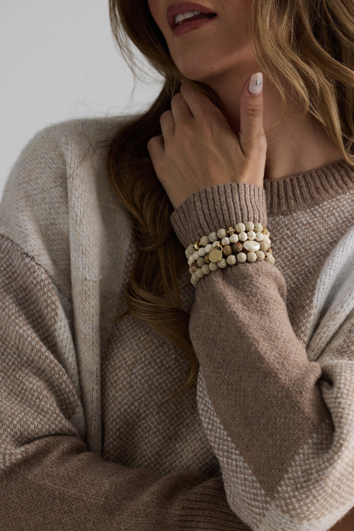 Model wearing Solaro Stack Bracelet in natural with natural stones and mother of pearl feature bead, on-wrist view on neutral background