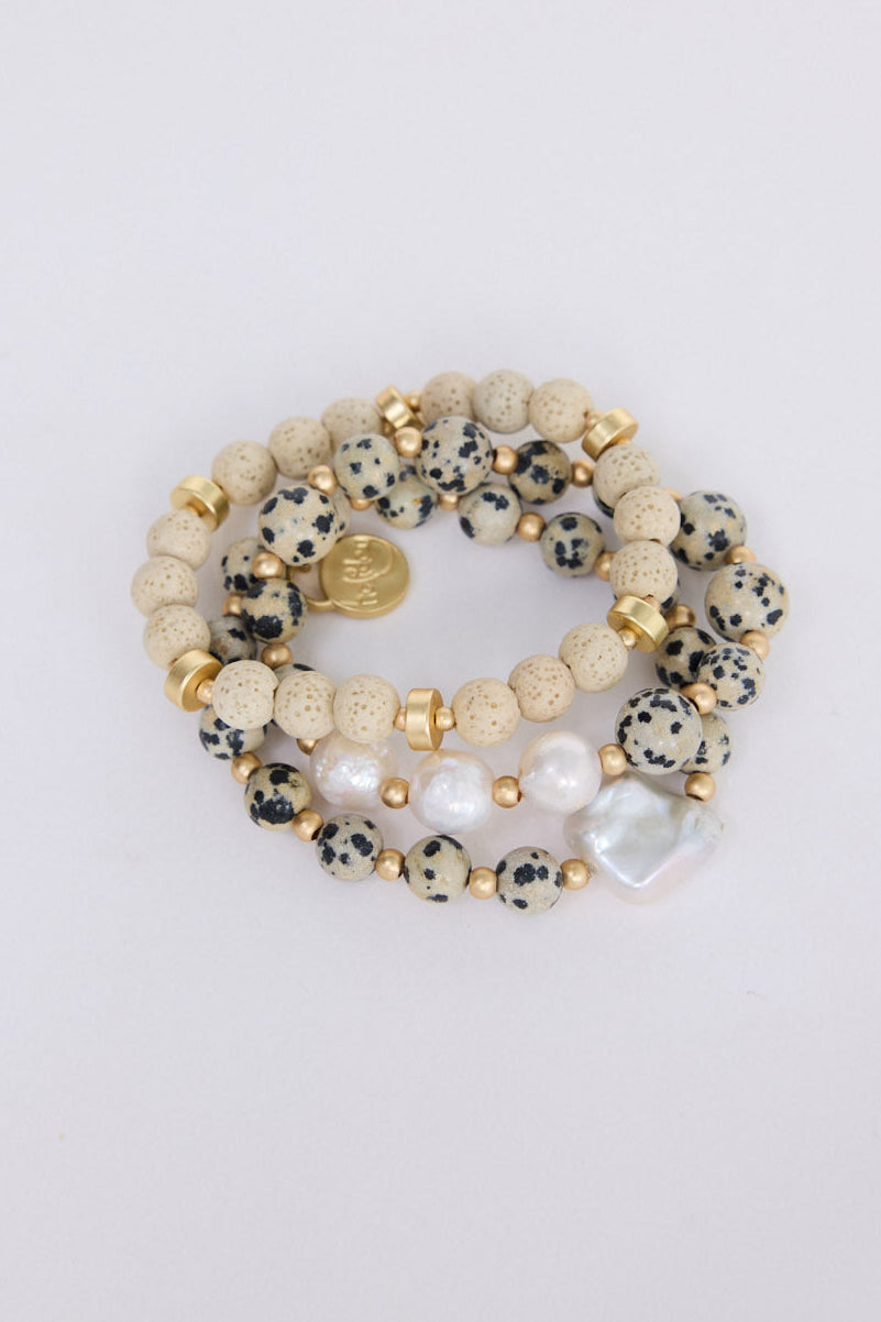 Model wearing Kendra Stack Bracelet in grey with natural stones and mother of pearl feature bead, alternate on-wrist view on neutral background