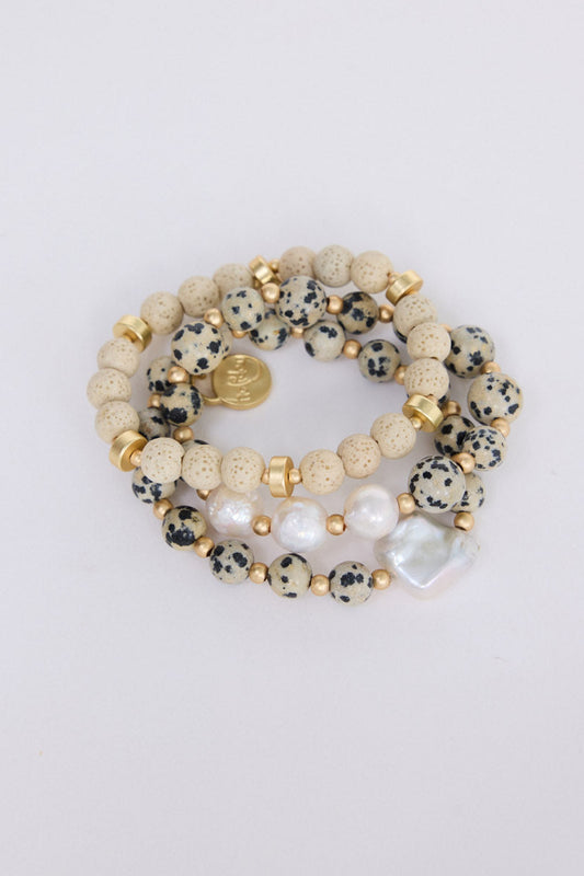 Model wearing Kendra Stack Bracelet in grey with natural stones and mother of pearl feature bead, alternate on-wrist view on neutral background