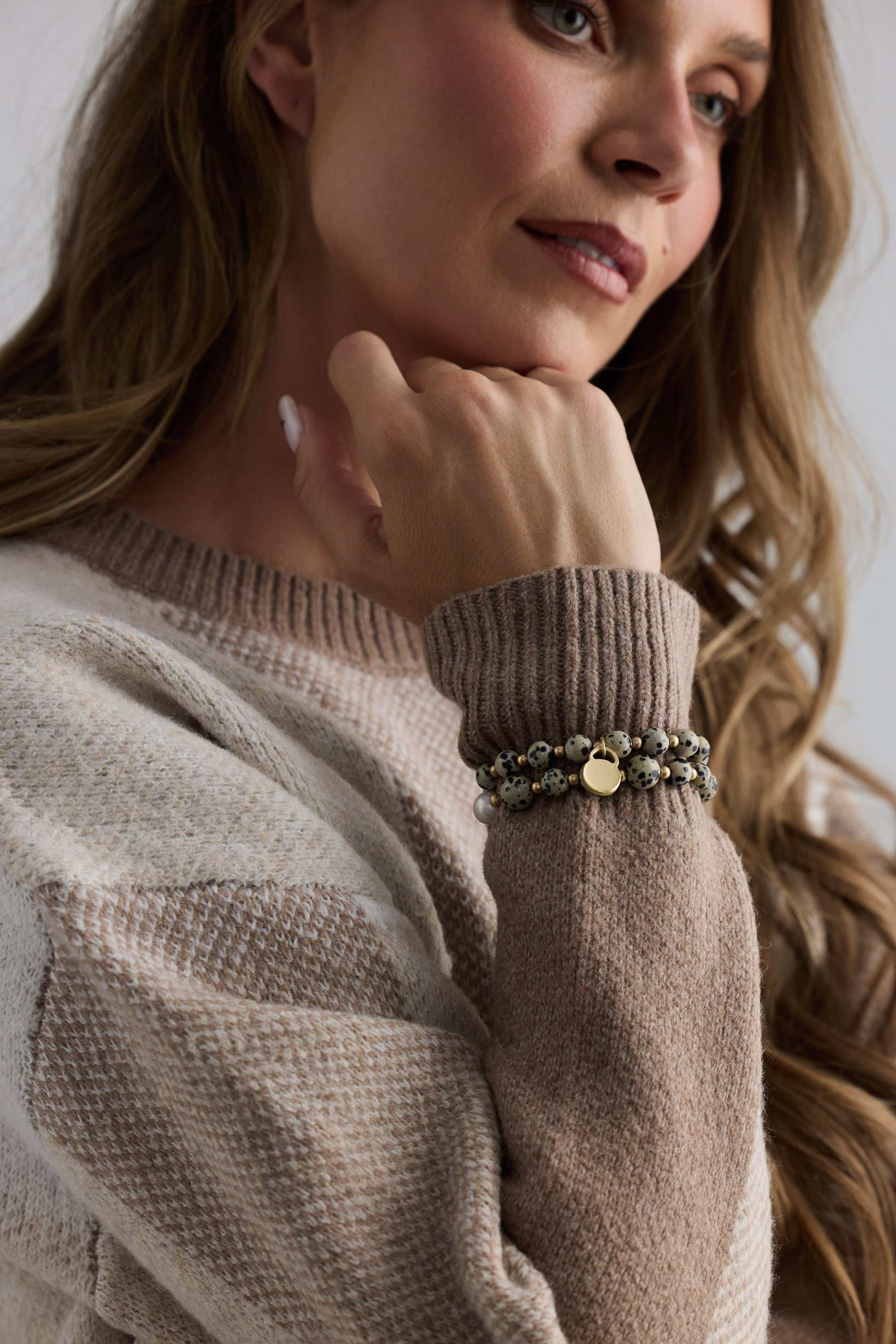 Model wearing Kendra Stack Bracelet in grey with natural stones and mother of pearl feature bead, stacked styling view on neutral background