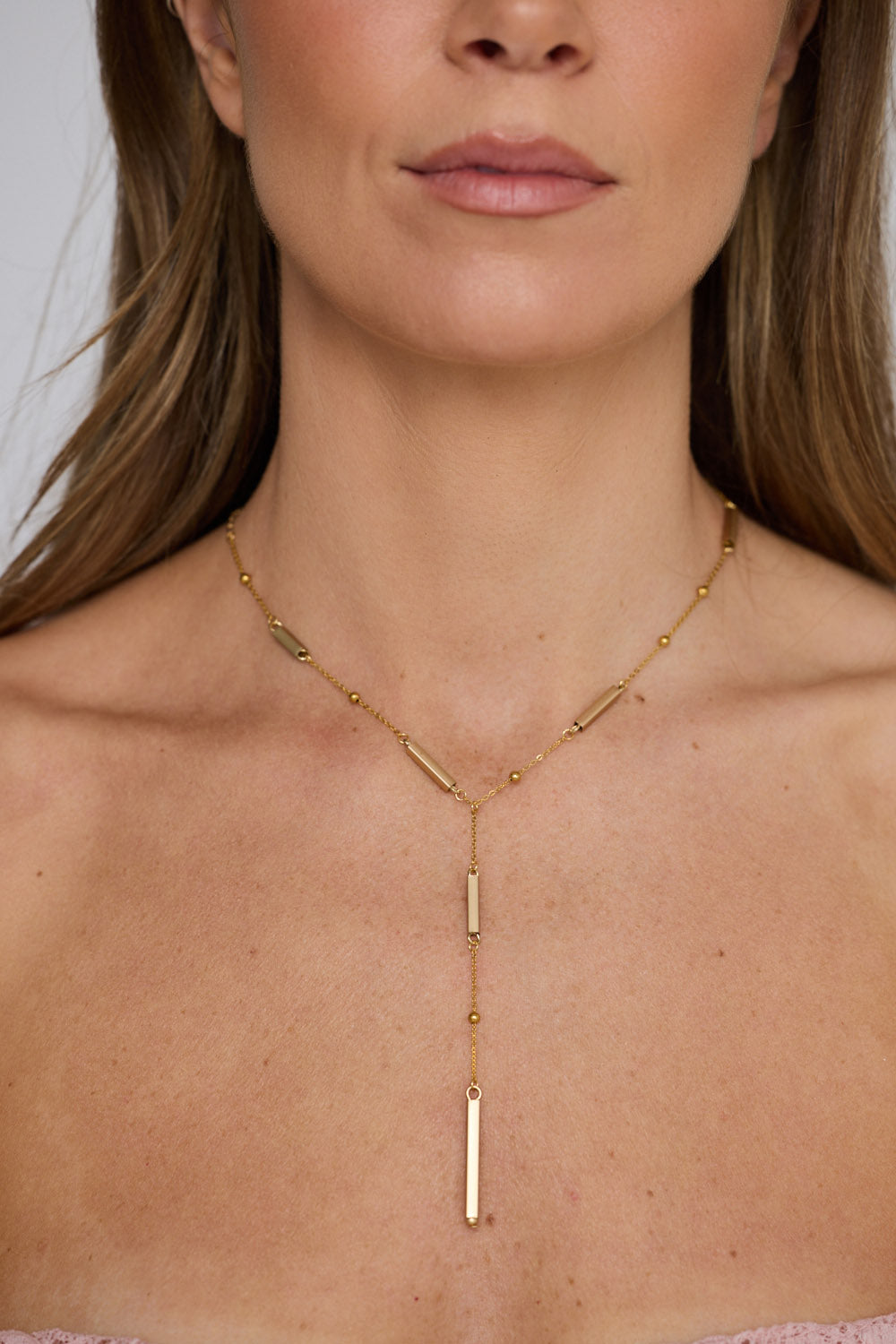 Bonita Necklace in gold with drop detailing, neckline styled view on neutral background