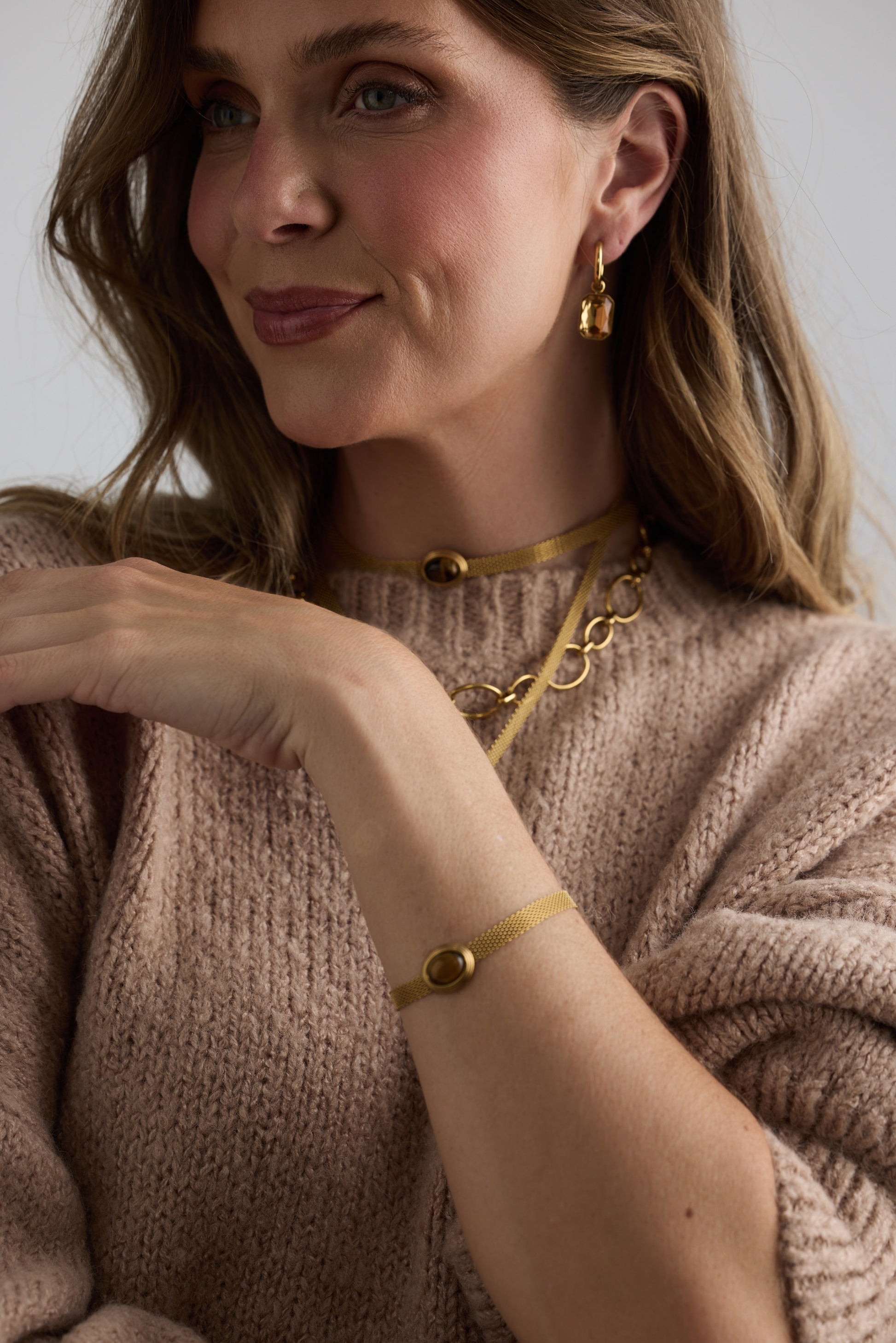 Model wearing Dorris Bracelet in amber with a central oval stone detail, detail on-wrist view on neutral background
