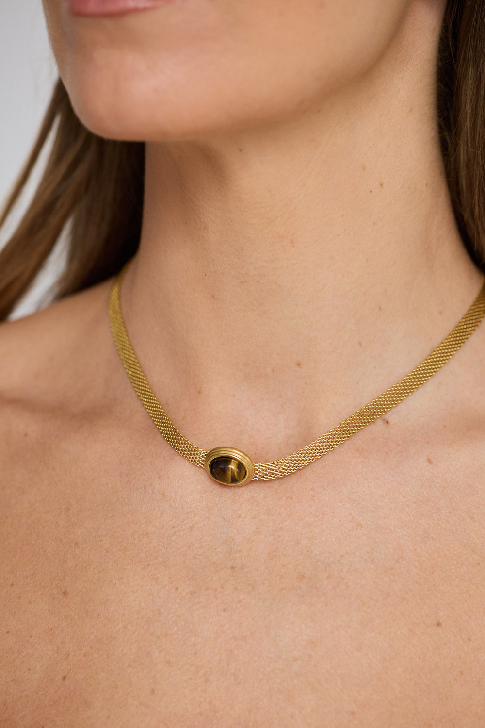 Dorris Necklace in amber with a central oval stone detail, neckline styled view on neutral background