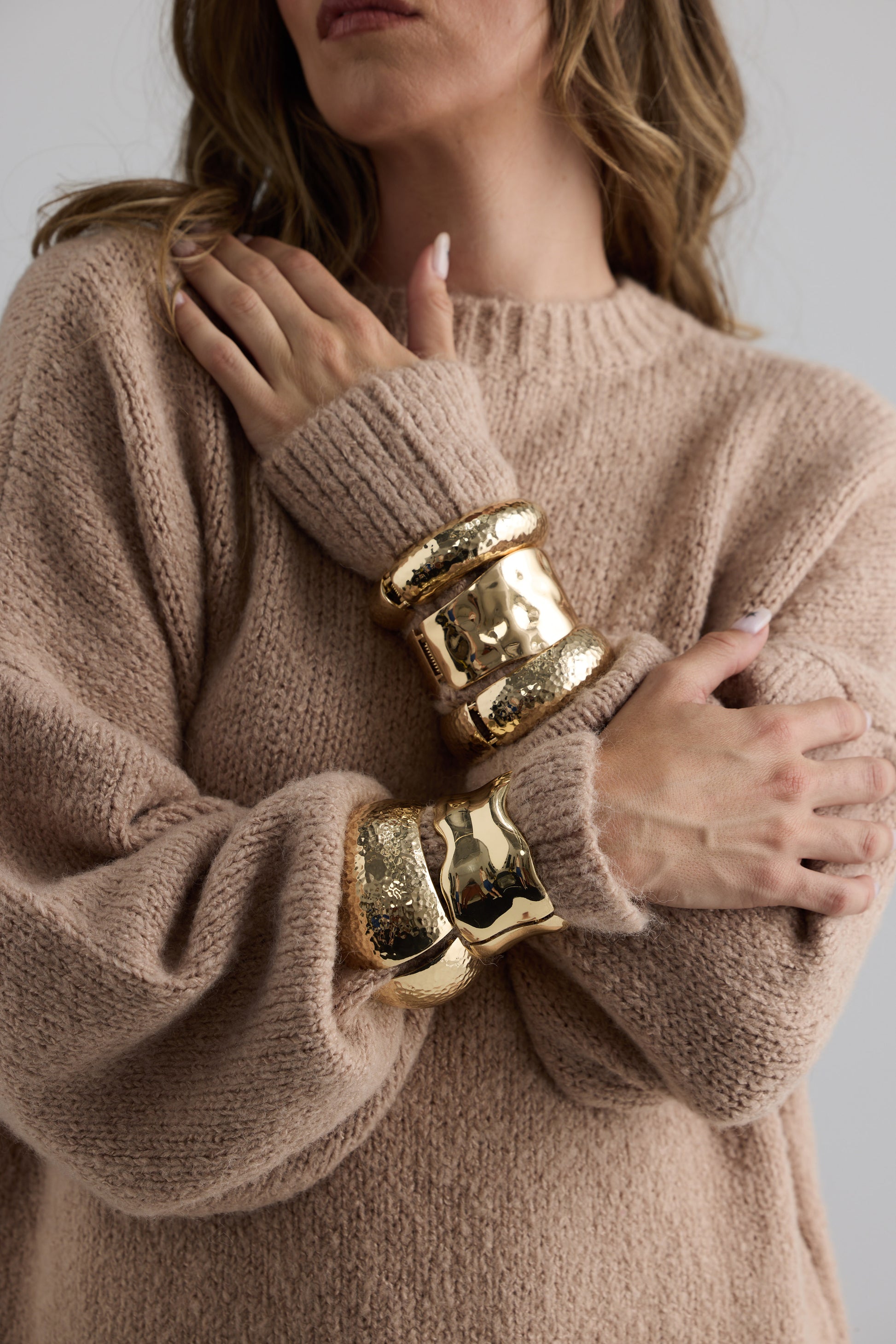 Model wearing Maura Bangle in gold with snap lock closure and hinge for easy wear, bracelet detail view on neutral background
