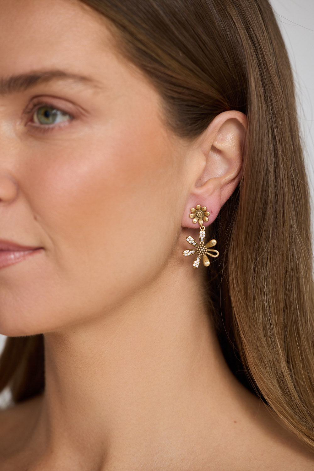 Close-up of a woman wearing gold earrings with a neutral background