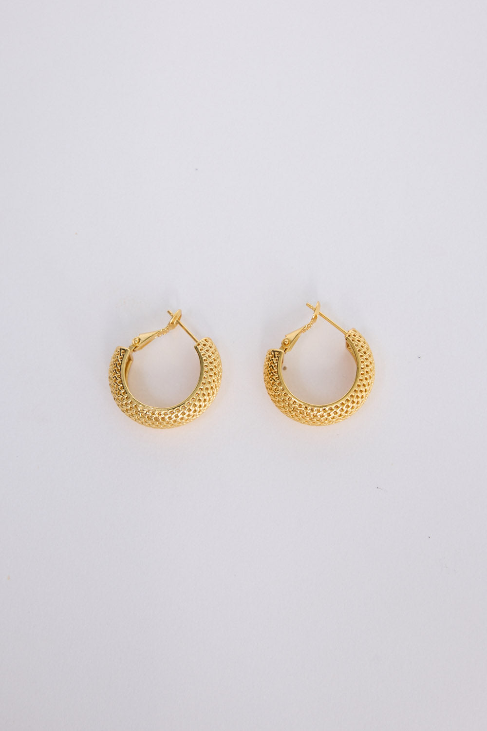 Sienna Earrings in gold with textured finish, angled view on white background