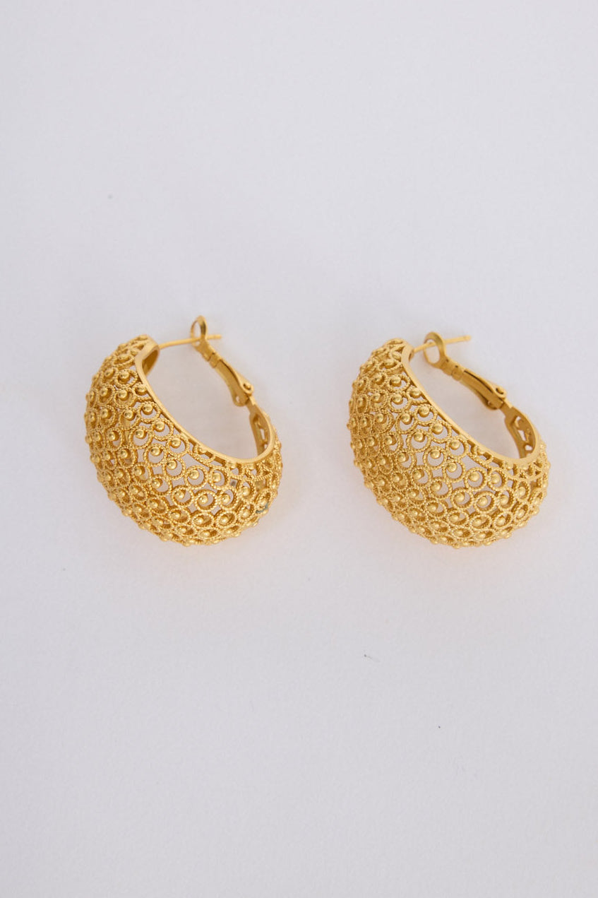 Model wearing Meadow Earrings in gold with woven texture detailing, ear detail view on neutral background