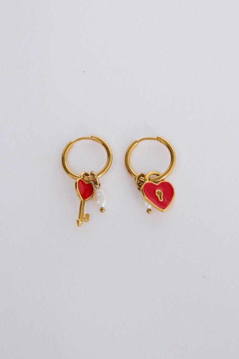 Lockheart Earrings in gold with heart and key charm detailing, angled view on white background
