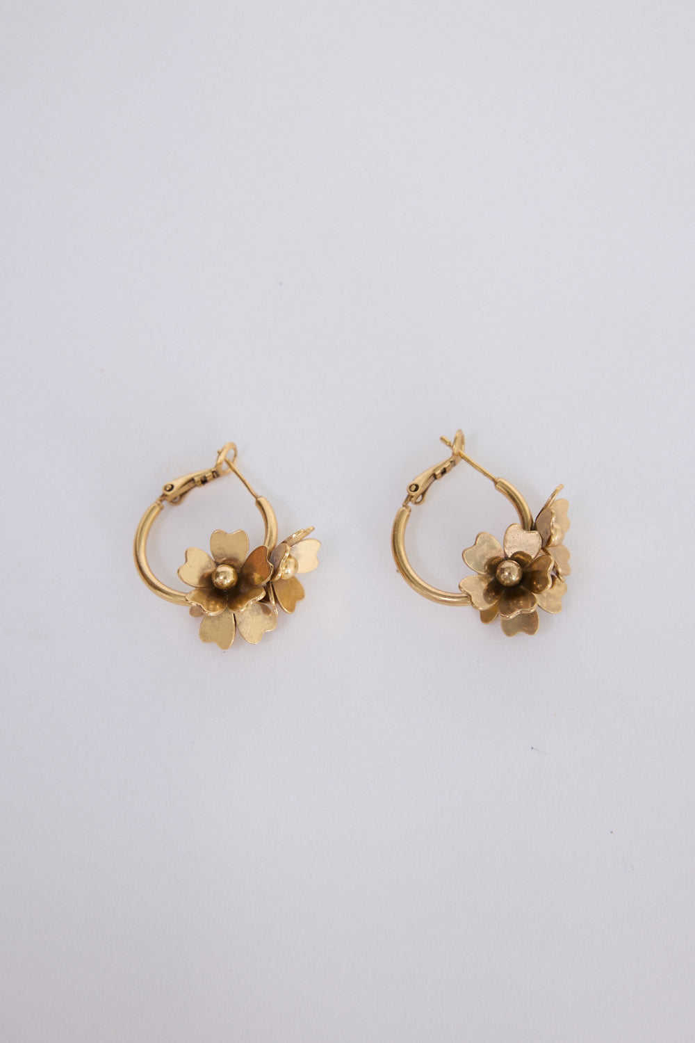 Model wearing Liucienne Earrings in gold with floral drop detailing, ear detail view on neutral background