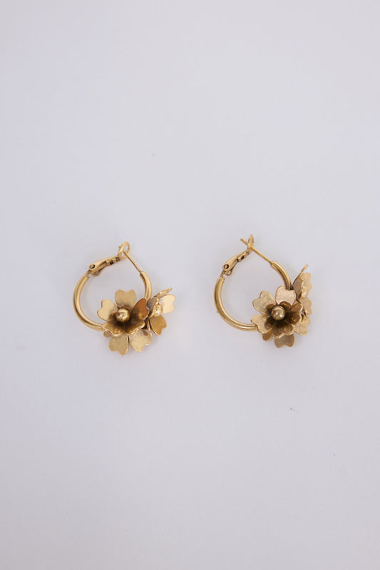 Model wearing Liucienne Earrings in gold with floral drop detailing, ear detail view on neutral background