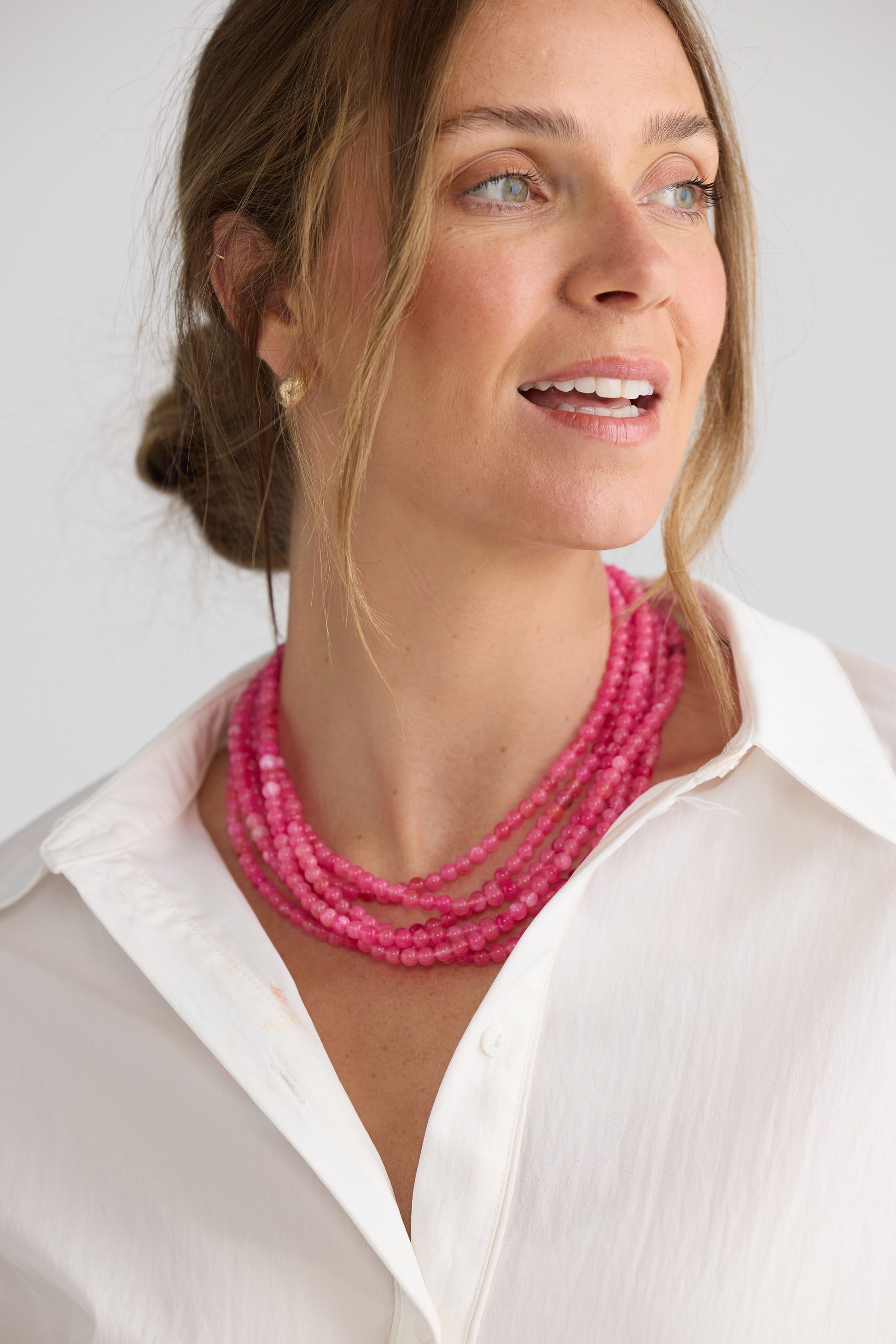Molly Necklace in hot pink with layered rows of fine rounded beads, neckline styled view on neutral background