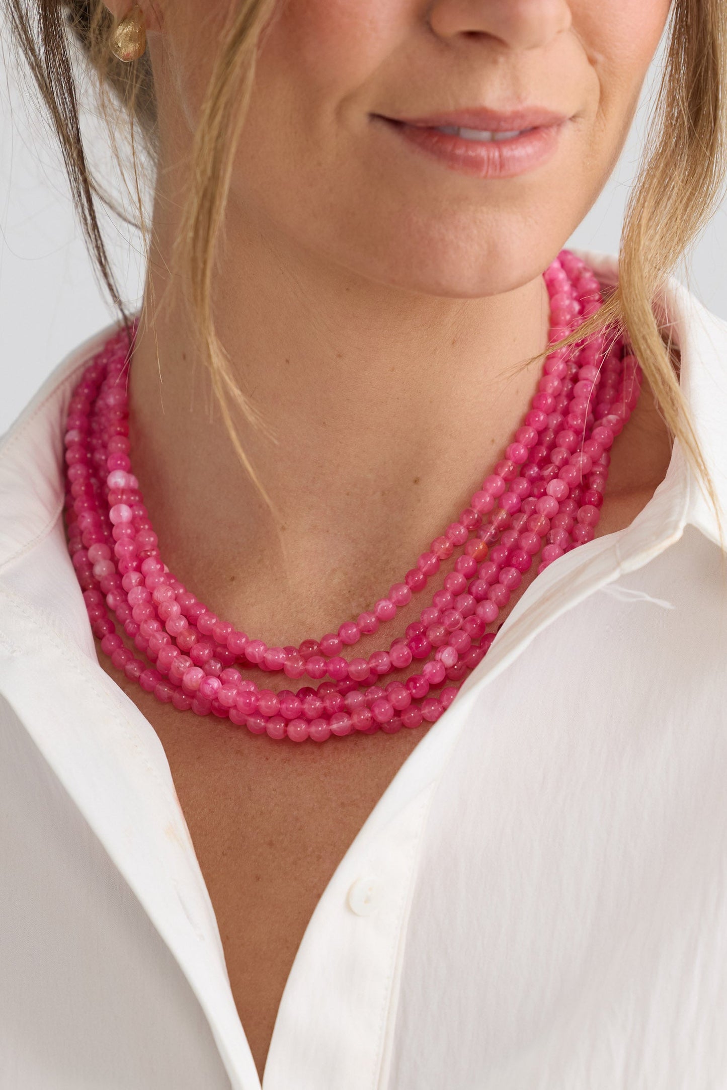Molly Necklace in hot pink with layered rows of fine rounded beads, side display view on neutral background