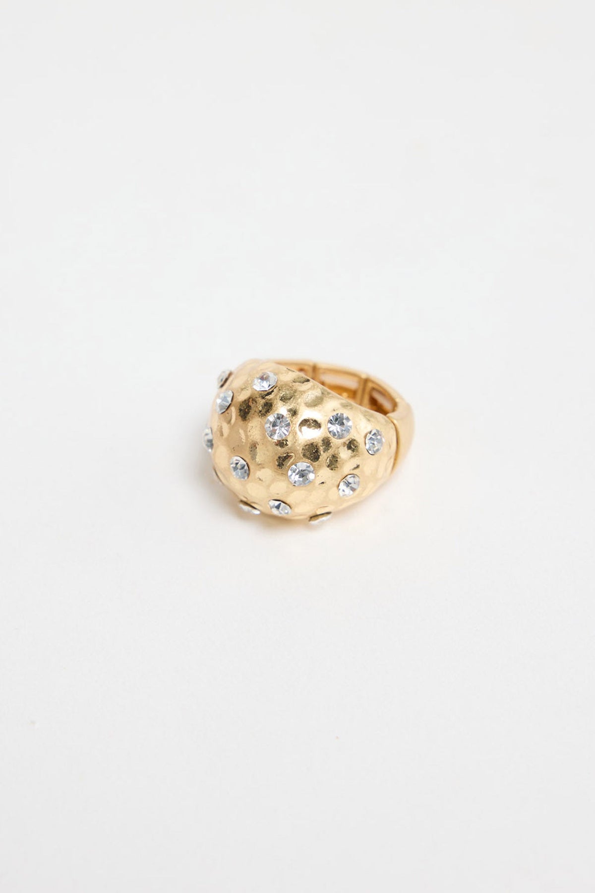 Domed gold-tone statement ring with a hammered texture and scattered clear crystal detailing, shown on a white background