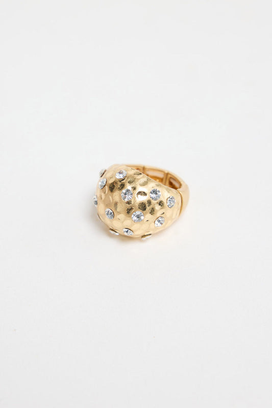 Domed gold-tone statement ring with a hammered texture and scattered clear crystal detailing, shown on a white background