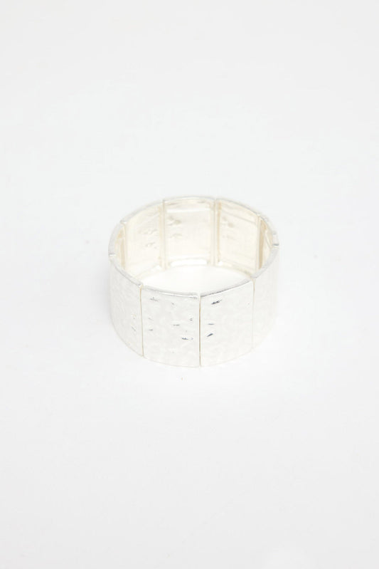 Wide stretch cuff bracelet made of large hammered silver-tone rectangular panels on an elastic band, shown at an angle on a white background