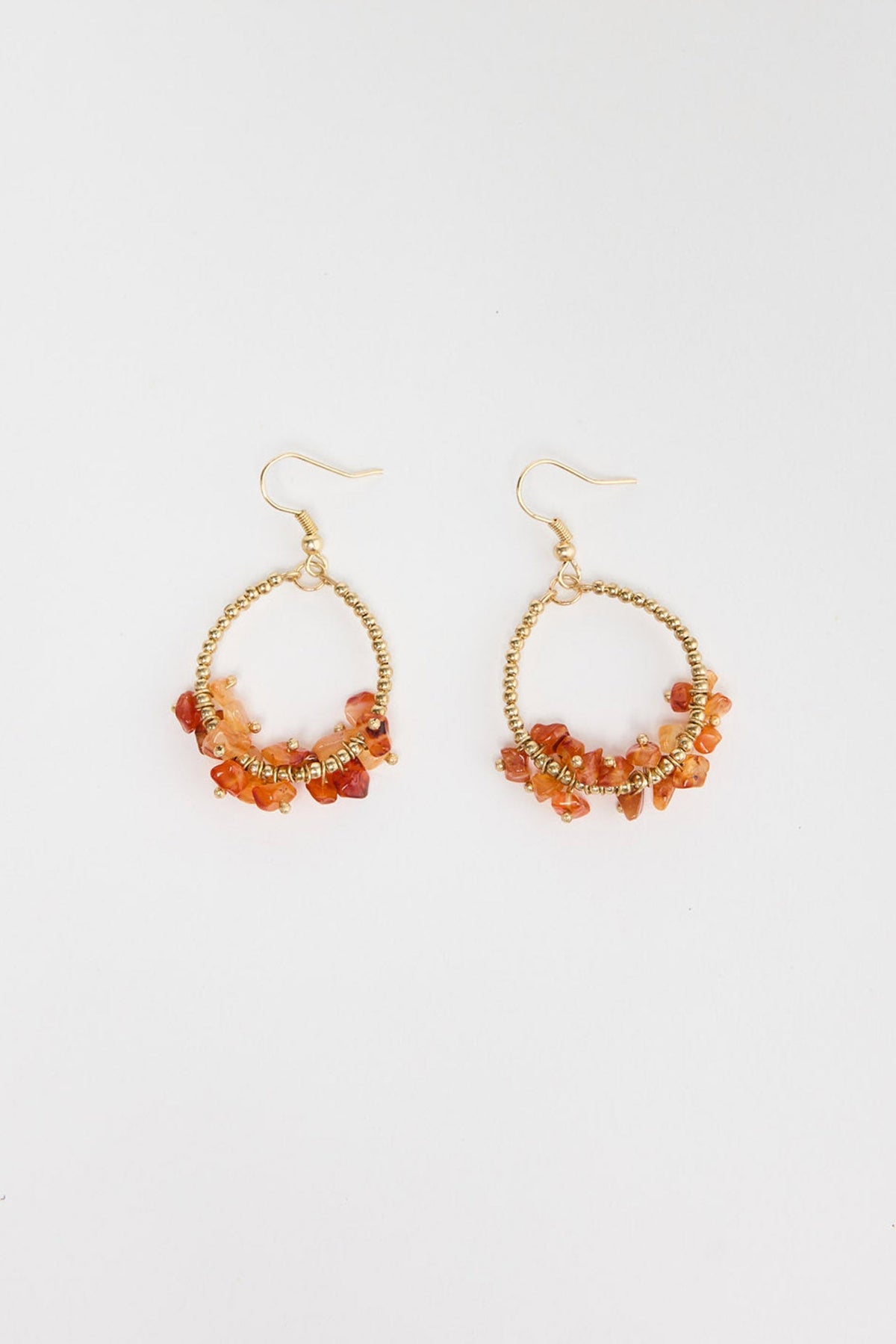 Pair of large gold-tone open hoop earrings with clustered orange carnelian stone chips wired along the lower half of the hoop, with a hook fastening, laid flat on a white background