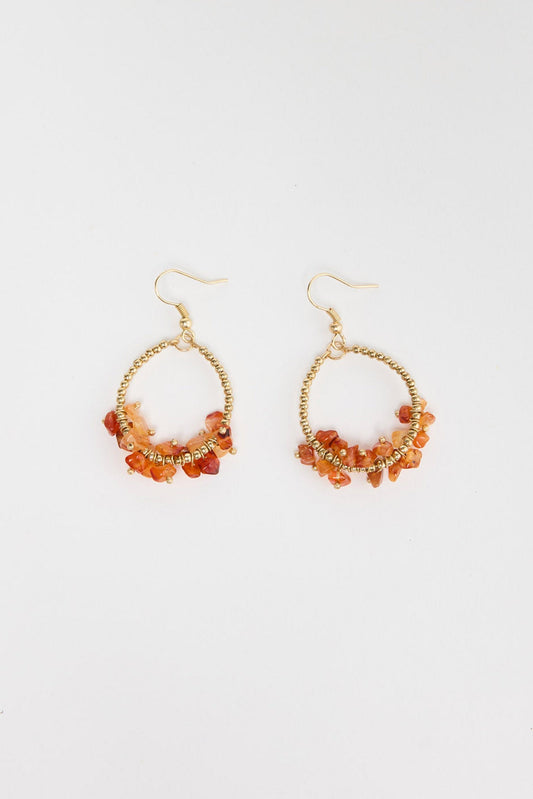 Pair of large gold-tone open hoop earrings with clustered orange carnelian stone chips wired along the lower half of the hoop, with a hook fastening, laid flat on a white background