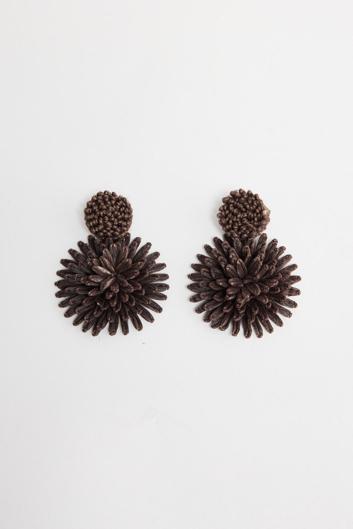 Pair of Polly statement earrings in Chocolate showing the woven raffia burst design and round textured stud