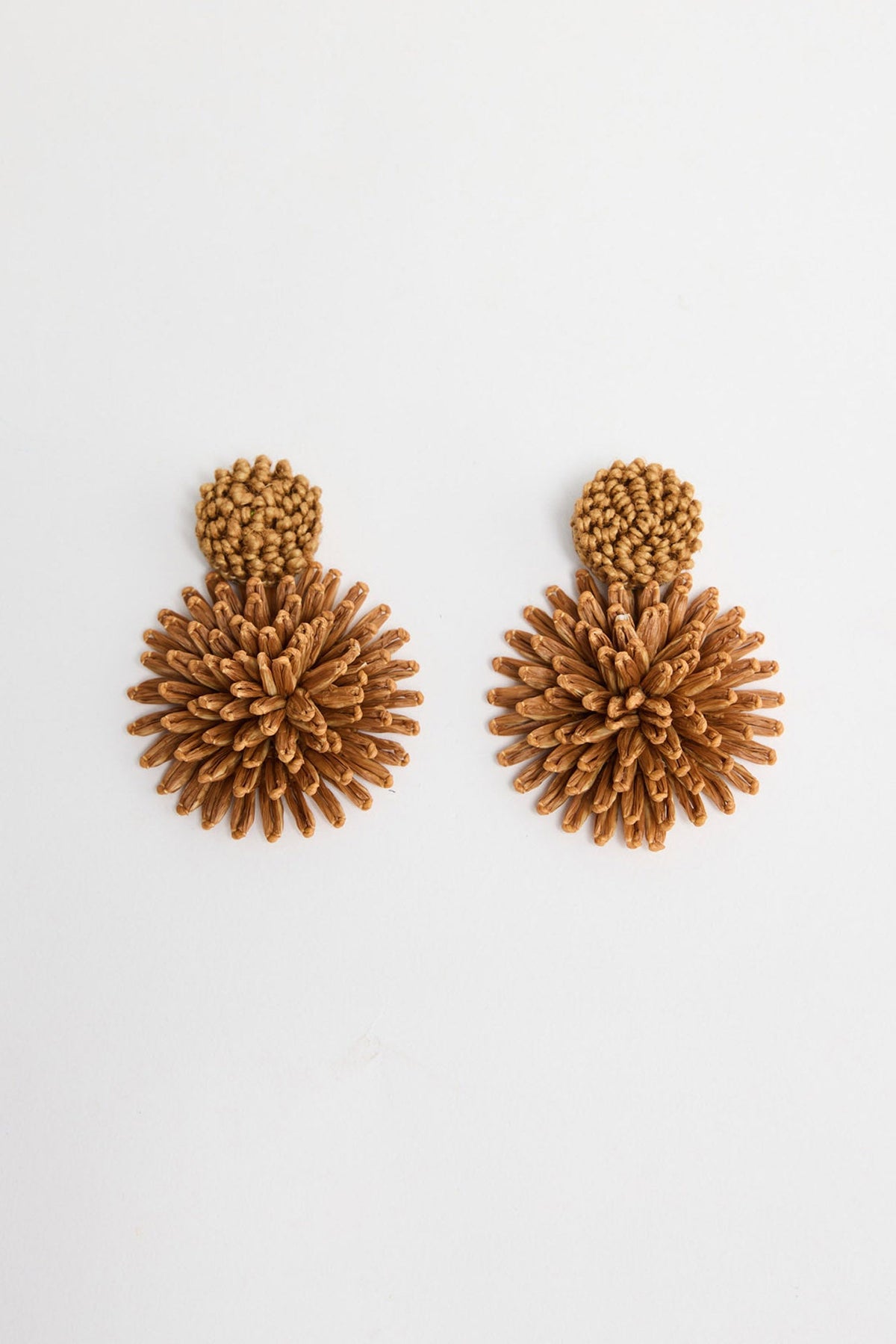 Pair of Polly statement earrings in Tan showing the woven raffia burst design and round textured stud on a white background