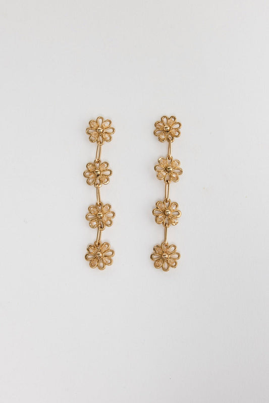 Pair of gold-tone Althea drop earrings laid flat, showing four cascading crystal-centre daisy links each