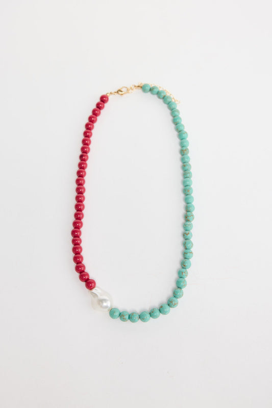 Silas beaded necklace laid flat, showing the two-tone aqua and red bead strand with a baroque pearl accent