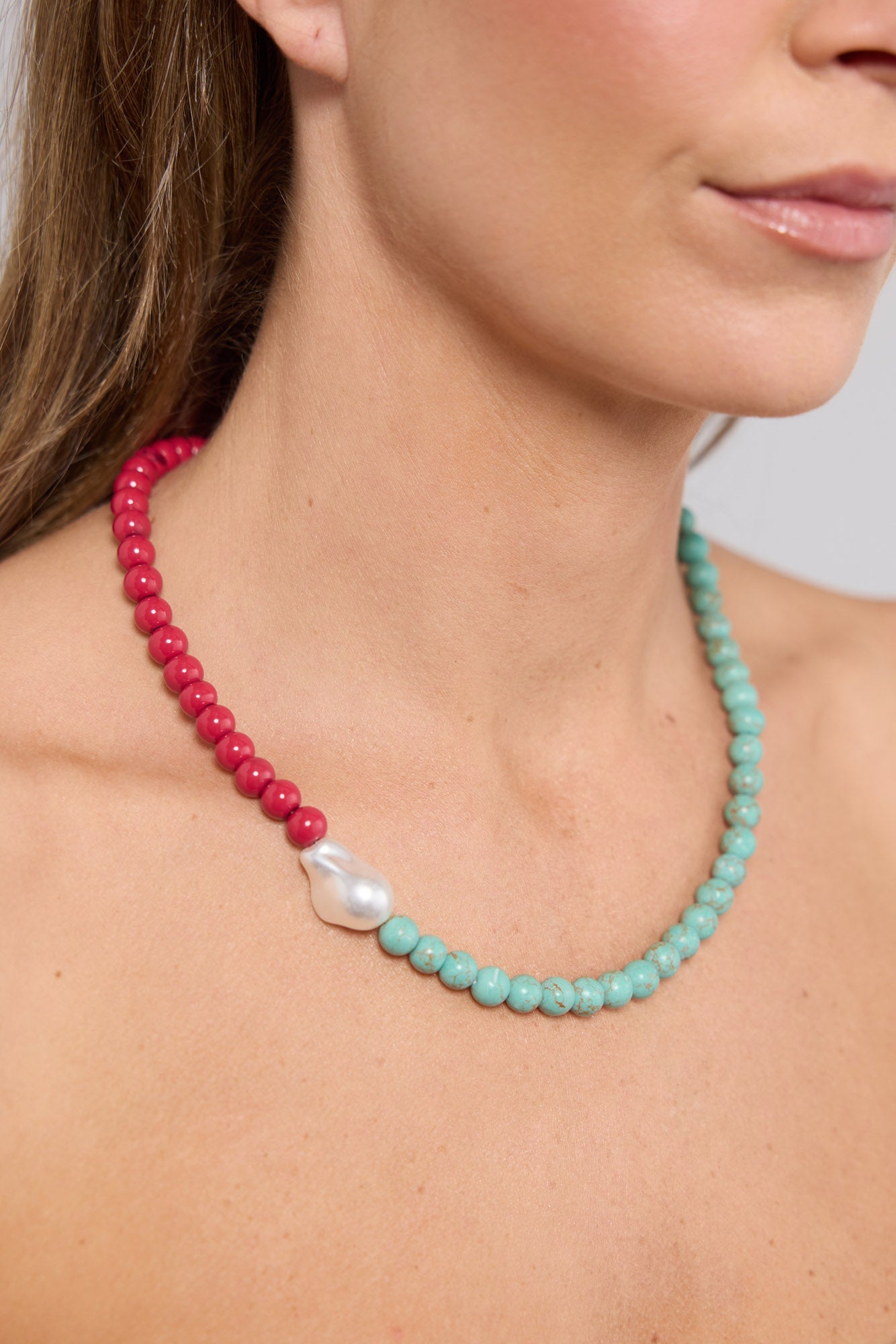 Close-up of the Silas Necklace in Aqua W Red worn at the neckline, showing the colour-block bead transition and pearl detail