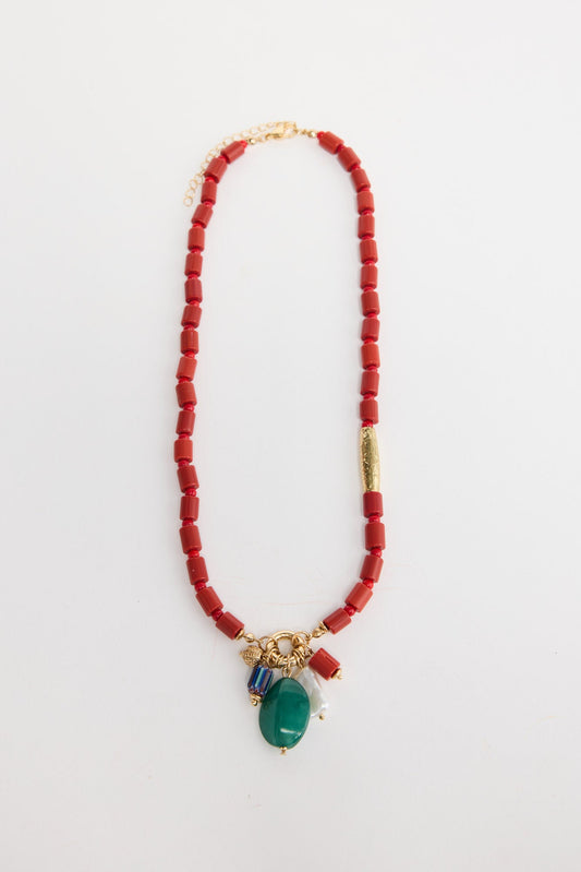 Elias beaded necklace laid flat, showing the red bead strand with a gold accent tube and a charm cluster of green stone, pearl and multicolour beads
